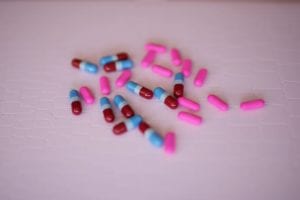  pink and red and blue capsules on a white background.