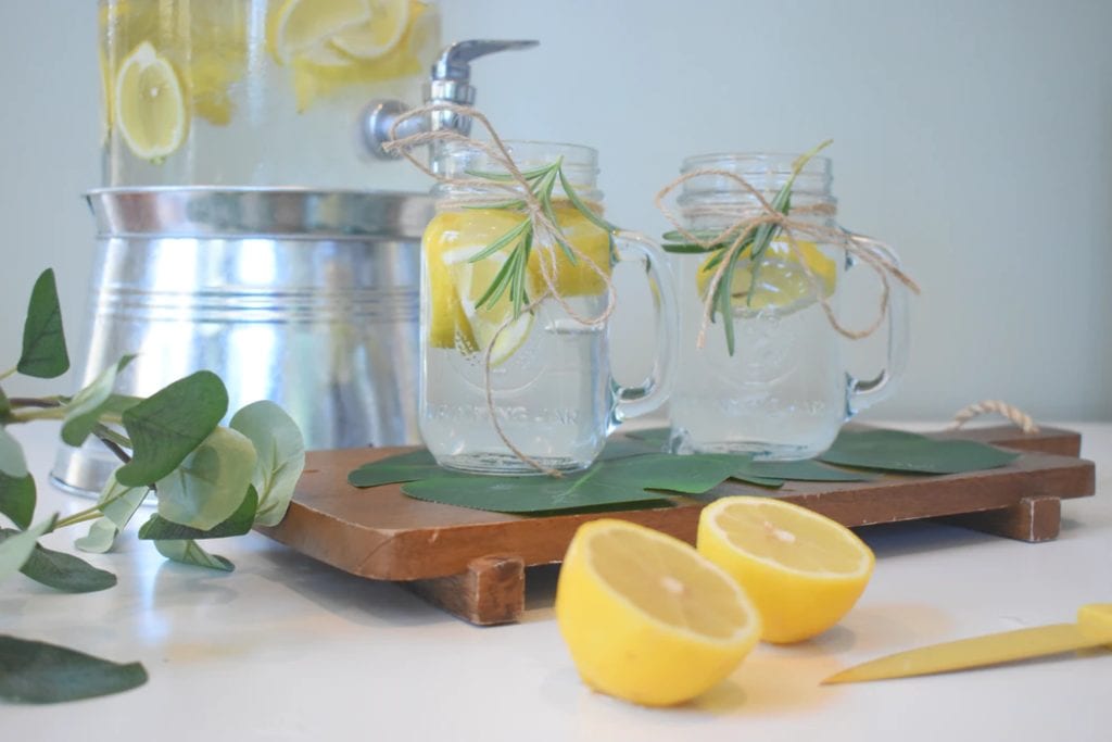 a water dispenser with sliced lemons for flavor. Two class mugs are near by